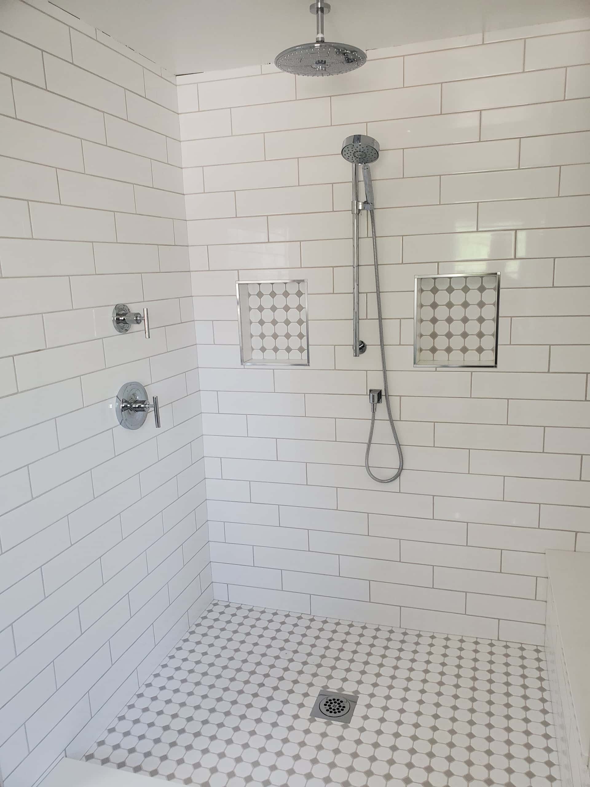 White subway tile walk-in shower with chrome rain head and penny tile floor in Lancaster, Ohio