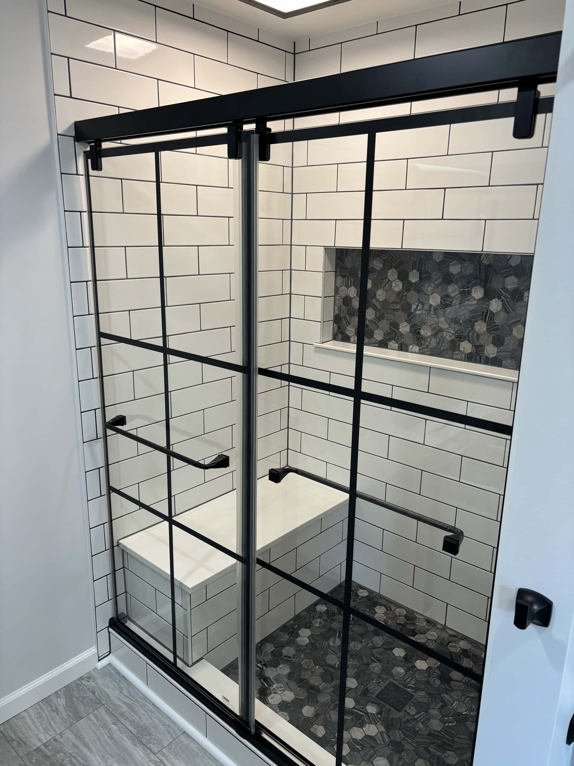 Walk-in shower with white subway tile and black grid sliding glass doors in Lancaster, Ohio