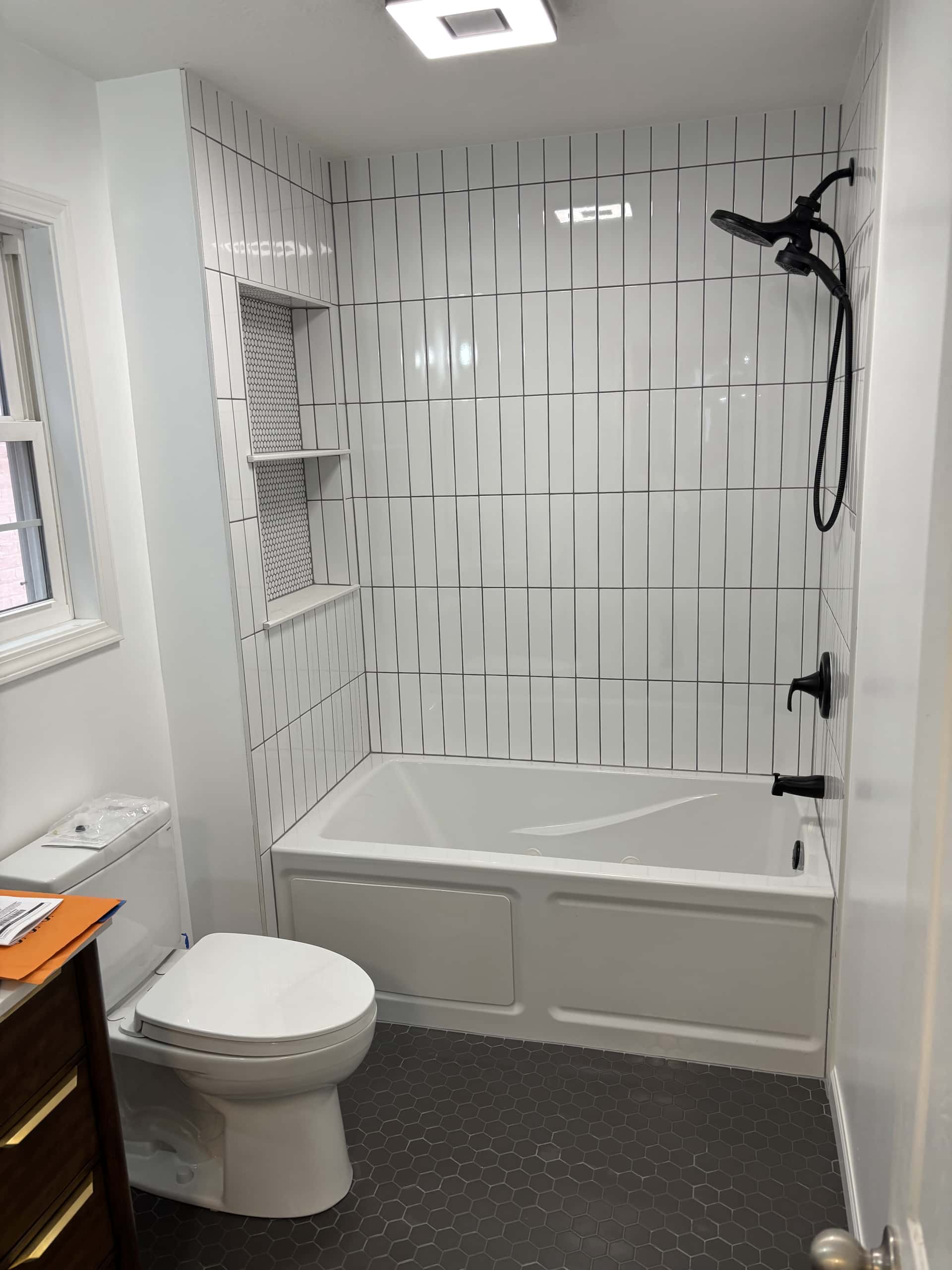 Tub and shower with vertical white tile surround and matte black fixtures in Lancaster, Ohio