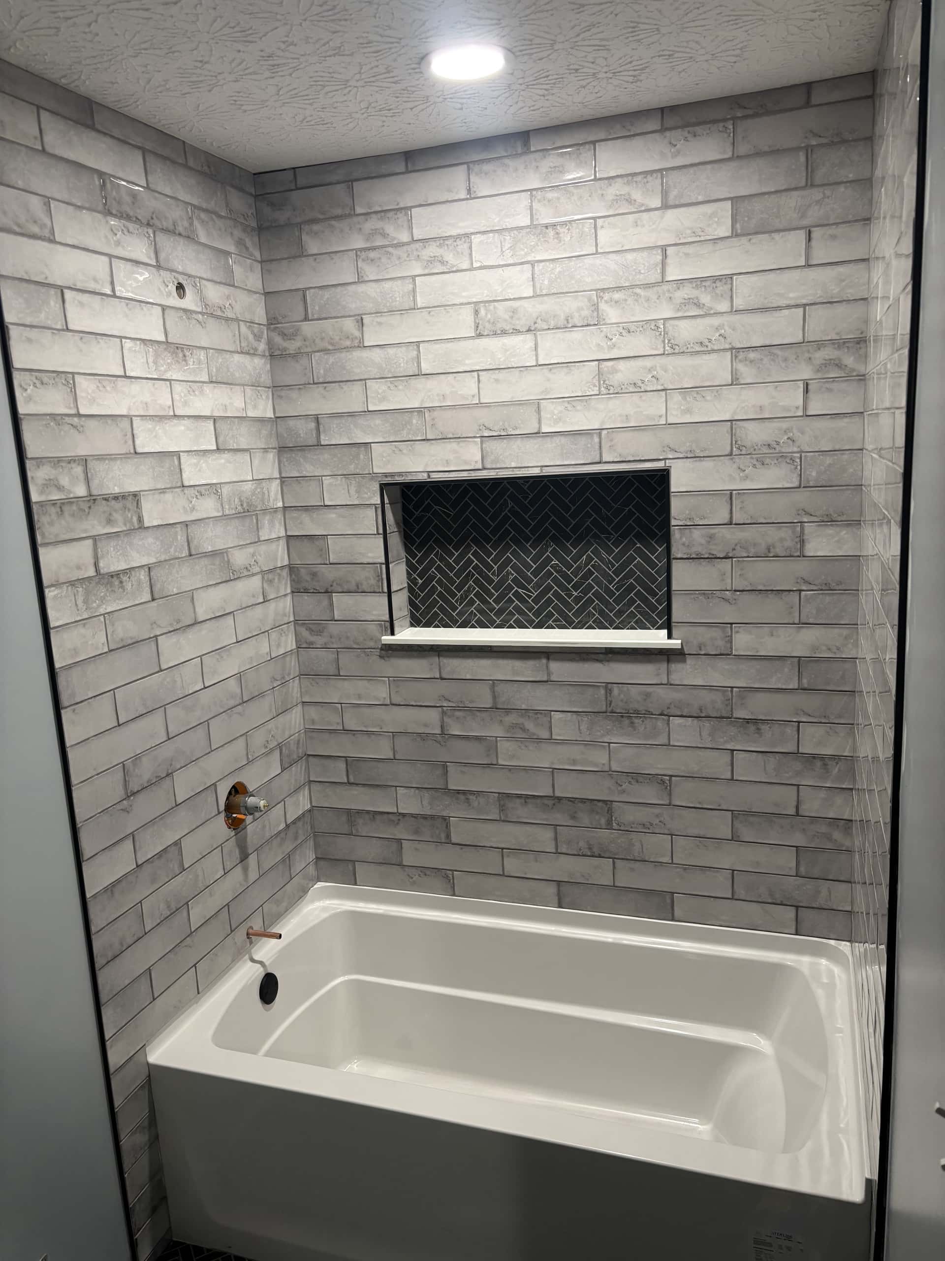 Tub and shower with gray marble-look tile and herringbone niche in Lancaster, Ohio