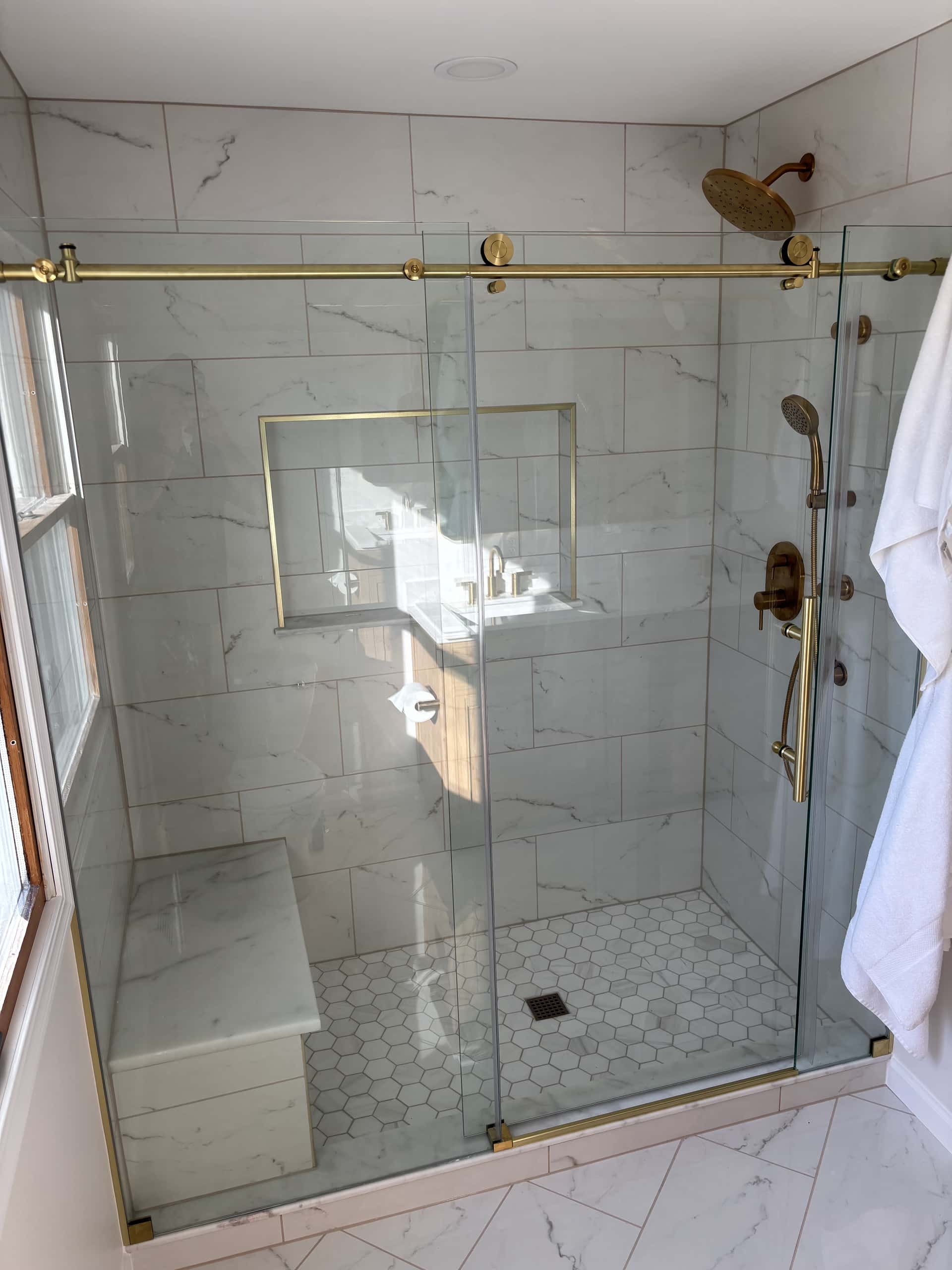Luxury walk-in shower with Carrara marble tile and brushed gold fixtures in Lancaster, Ohio