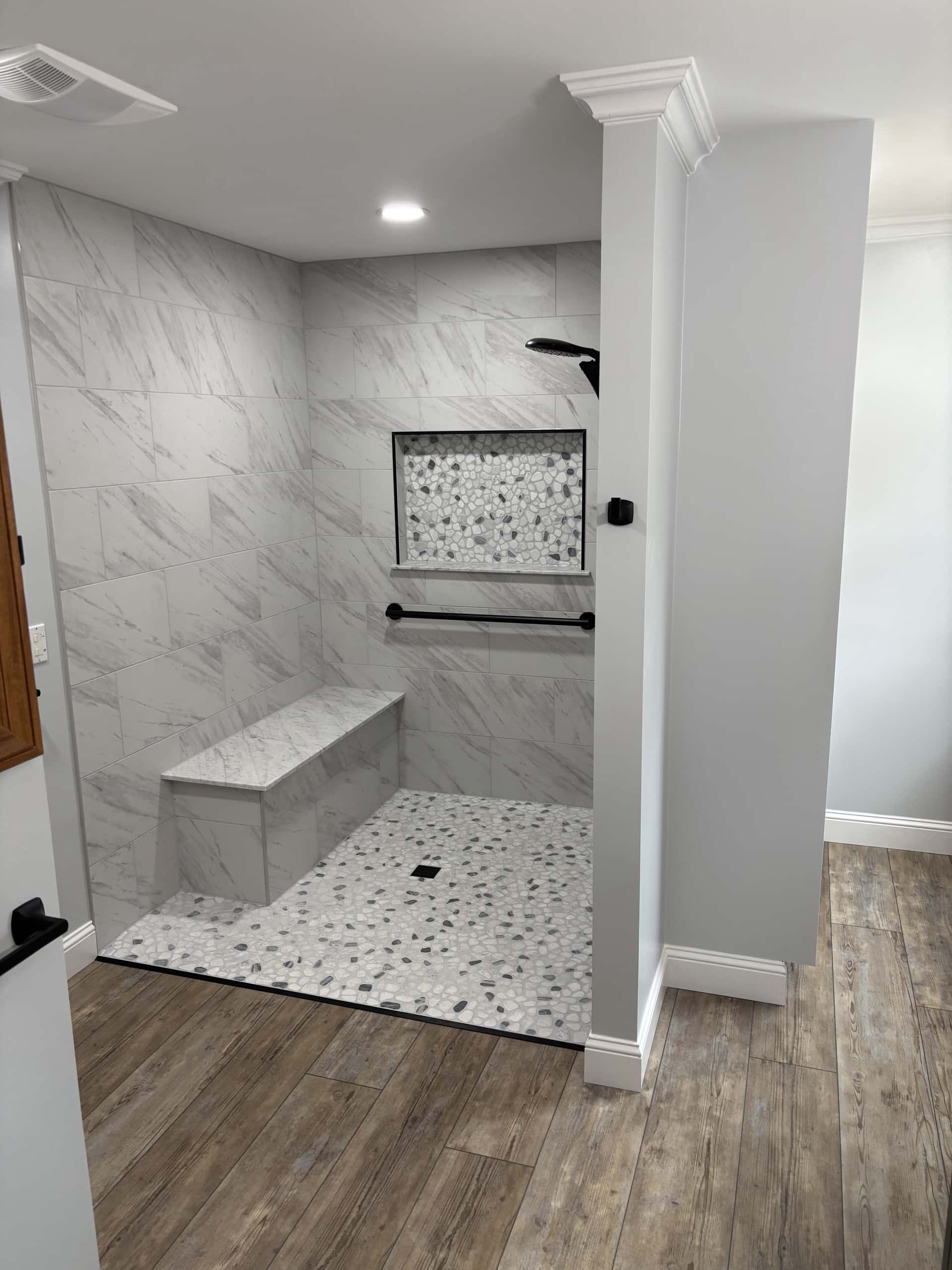Open walk-in shower with marble tile and pebble stone floor in Lancaster, Ohio