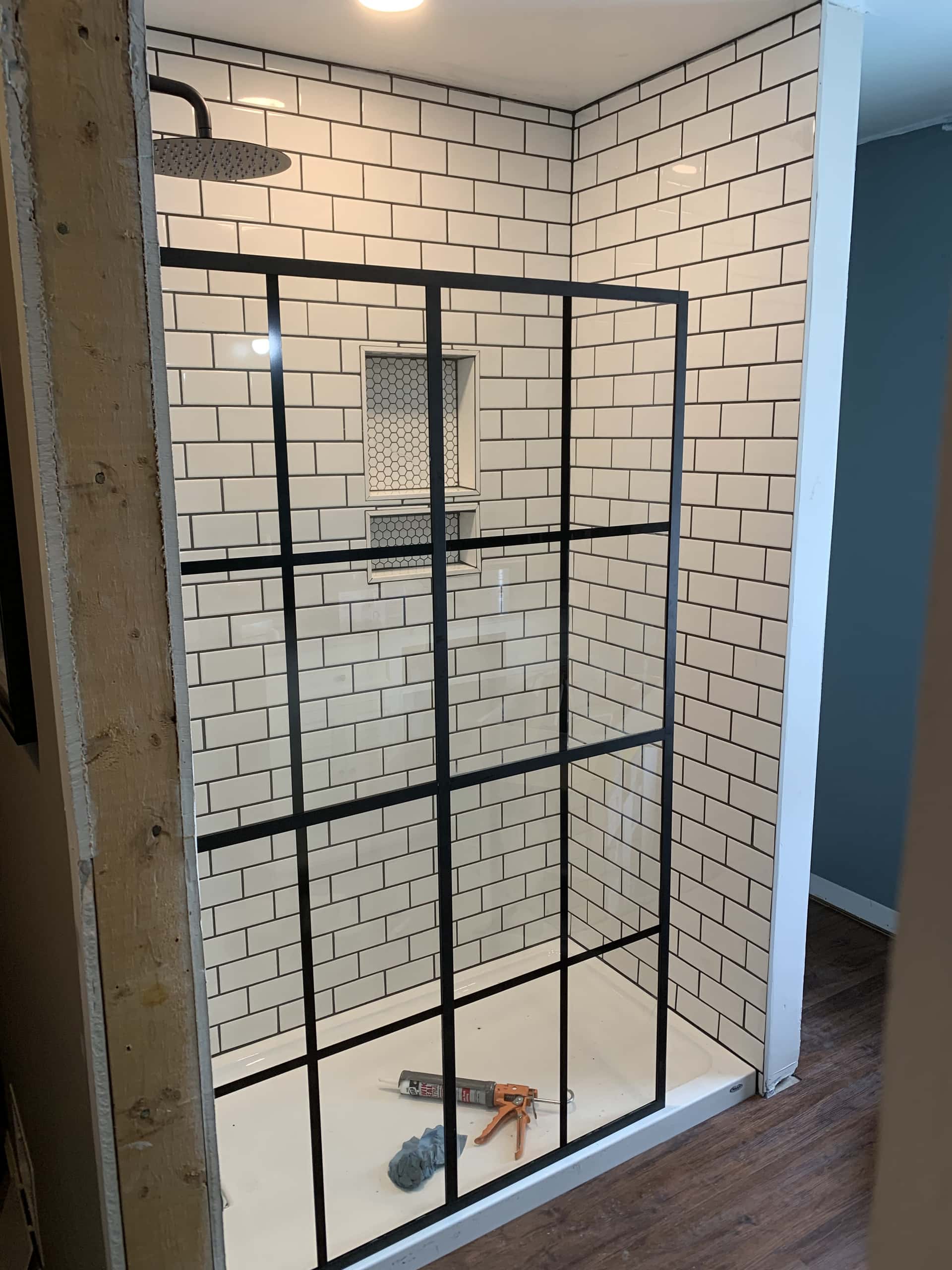 Walk-in shower with white subway tile and black grid glass panel in Lancaster, Ohio