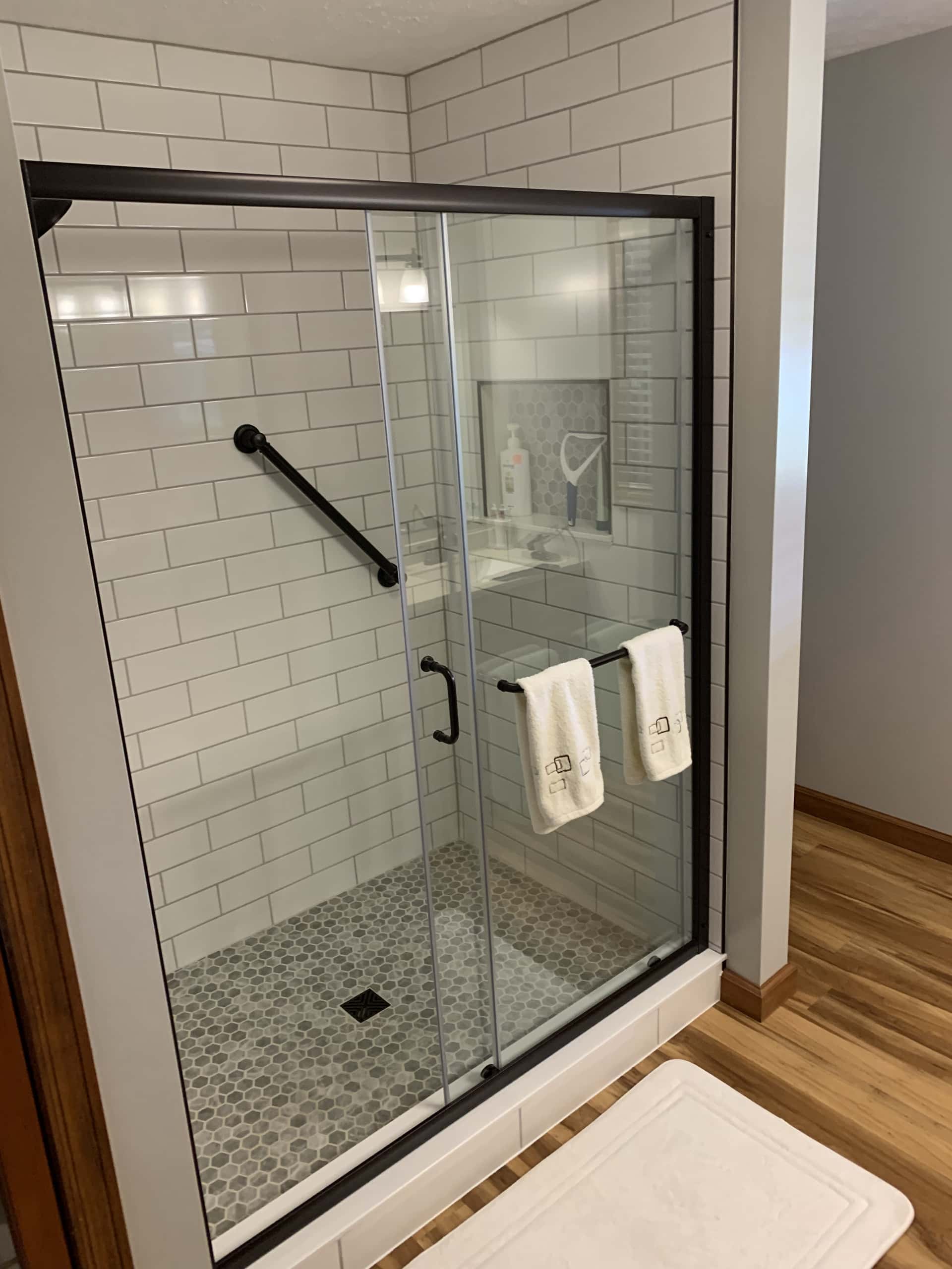 Walk-in shower with white subway tile and sliding black frame glass in Lancaster, Ohio