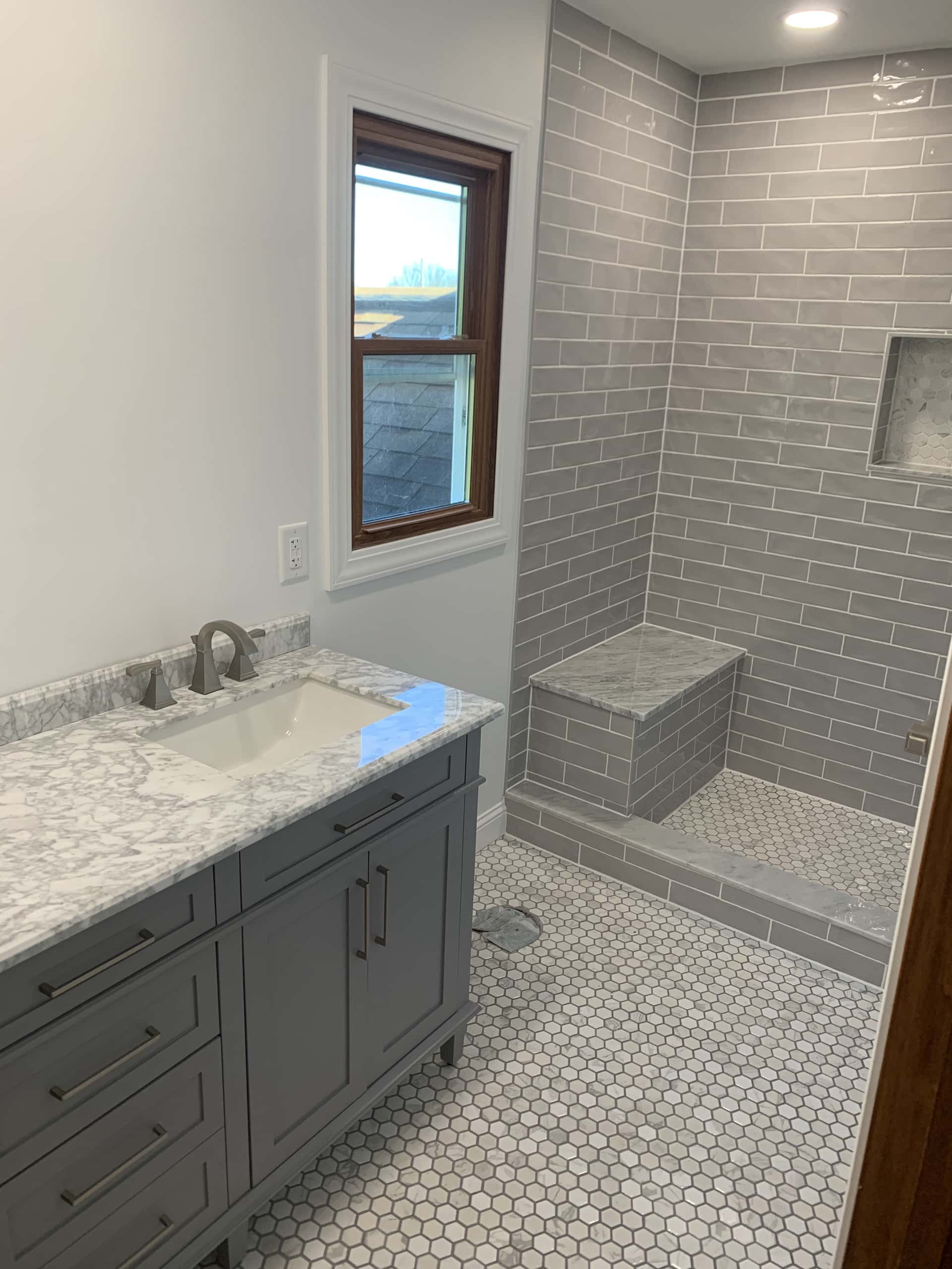 Gray subway tile walk-in shower with built-in marble bench and vanity in Lancaster, Ohio